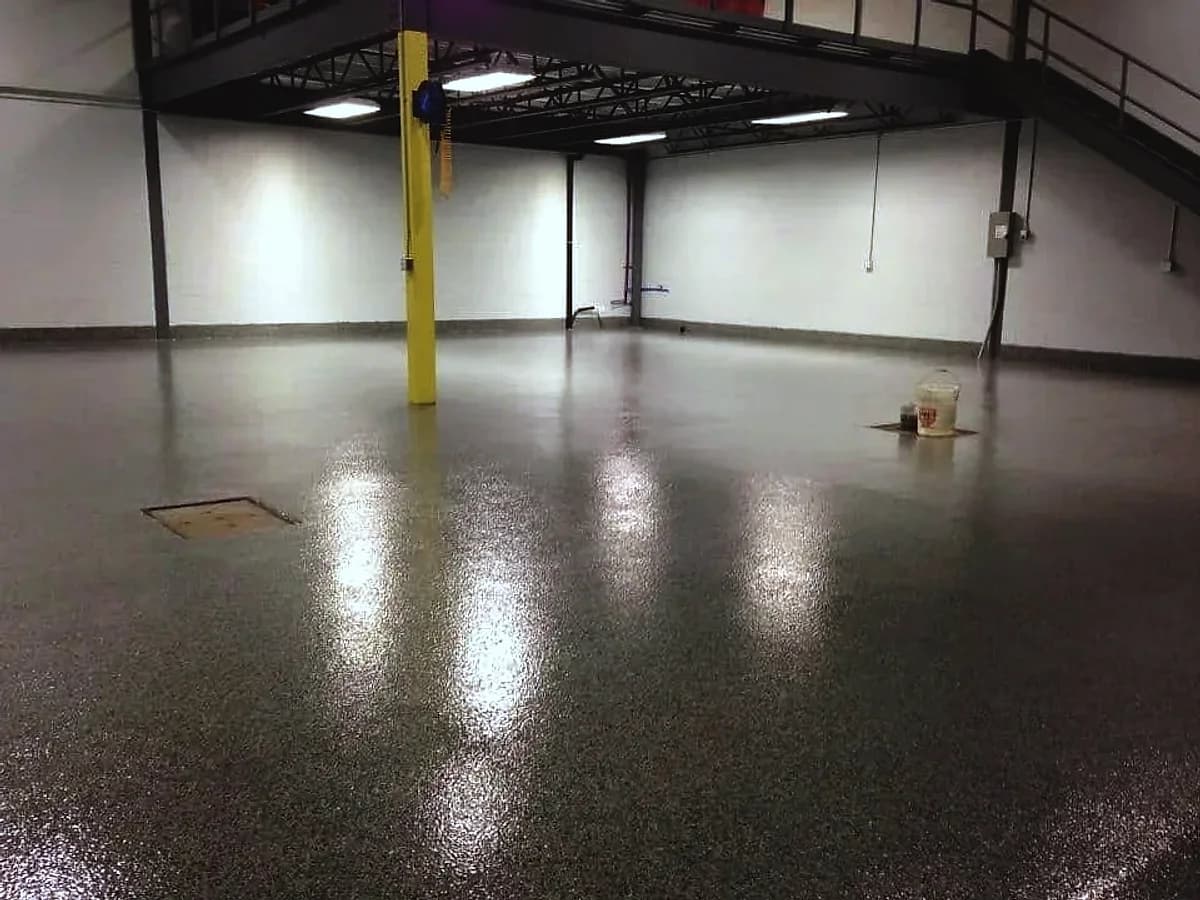 An industrial plant room with a dark flake floor, a yellow column and a steel mezzanine above