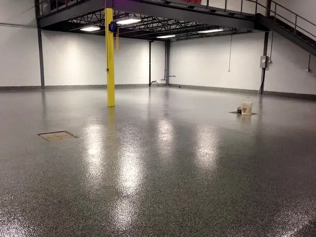 An industrial plant room with a dark flake floor, a yellow column and a steel mezzanine above