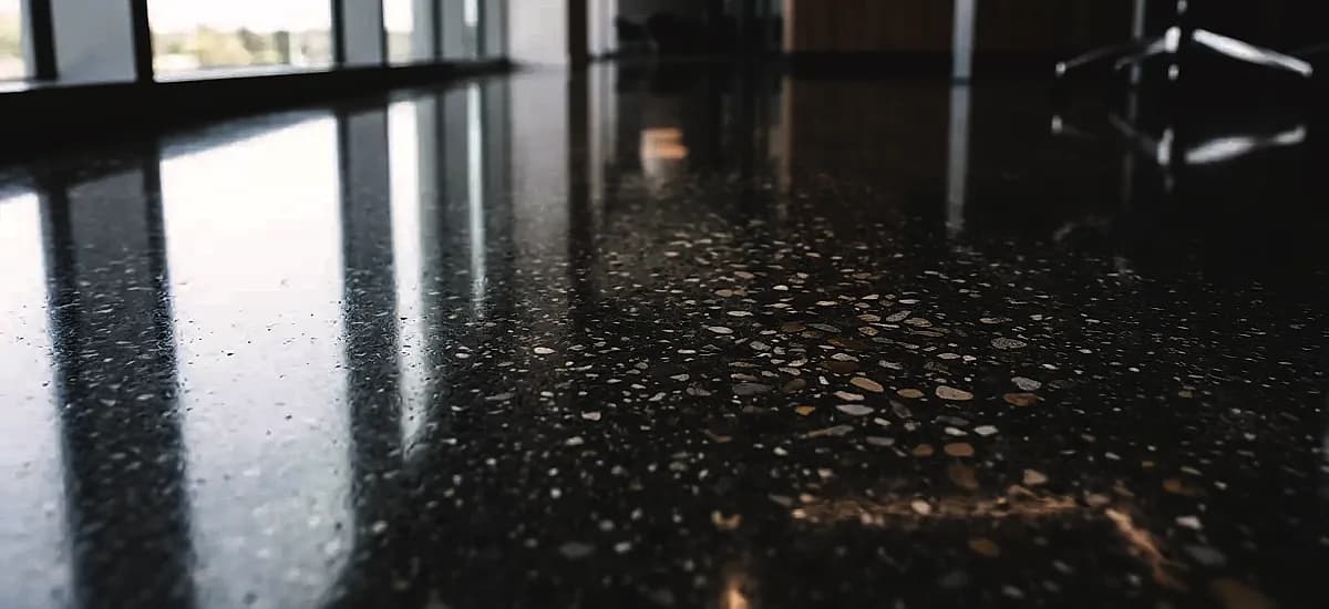 Close-up of a high gloss polished concrete floor showing mirror-like light reflectivity and aggregate exposure
