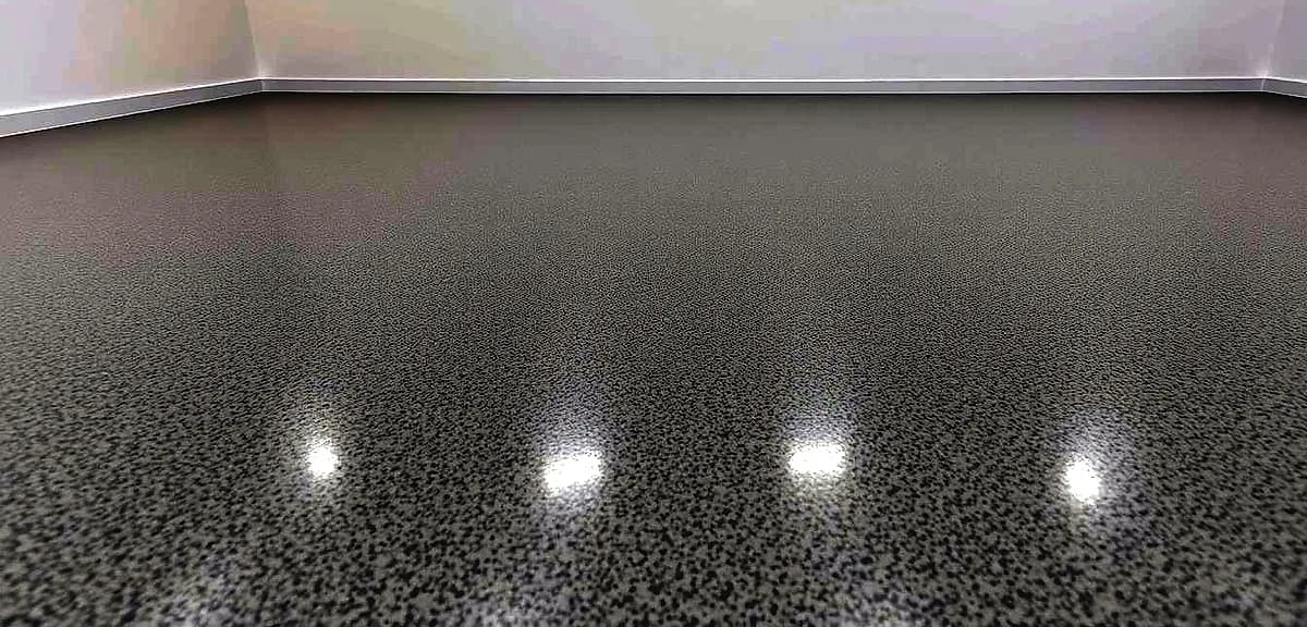 A high-quality commercial epoxy floor, characterized by a glossy, seamless finish, contrasts sharply with a more textured, matte-like residential epoxy