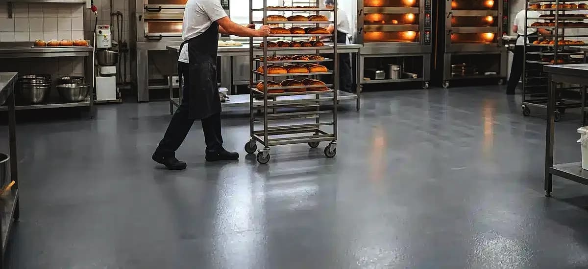 Seamless urethane cement flooring installed in a commercial bakery with stainless steel ovens and rolling racks