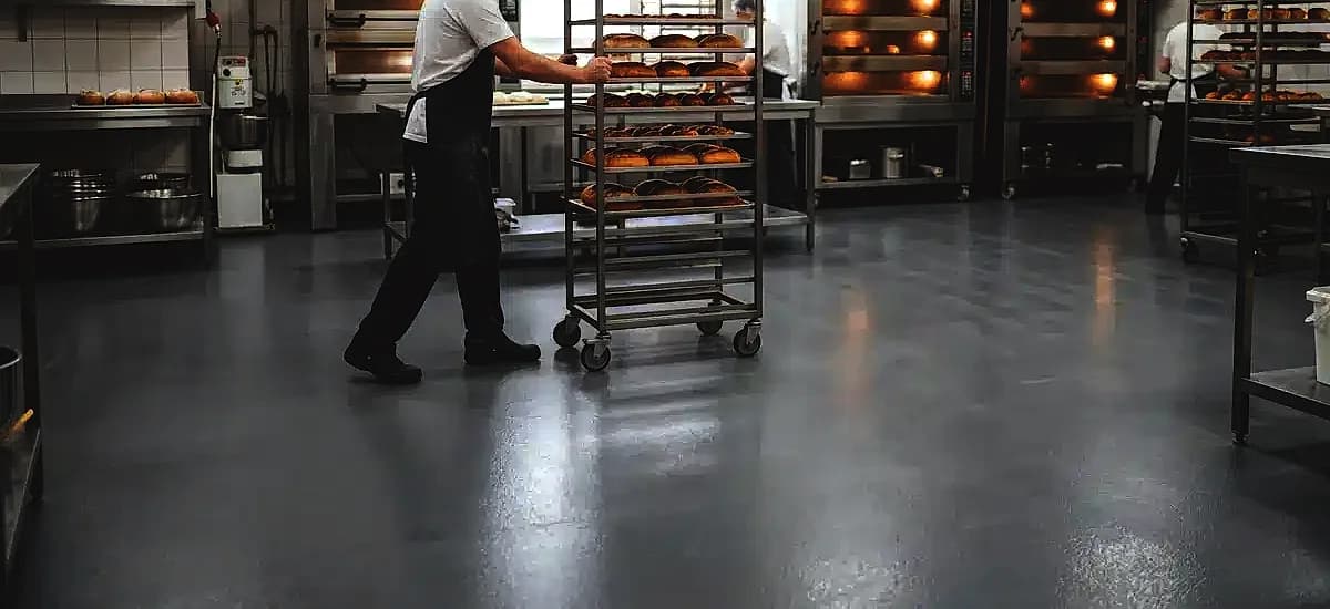 Seamless urethane cement flooring installed in a commercial bakery with stainless steel ovens and rolling racks