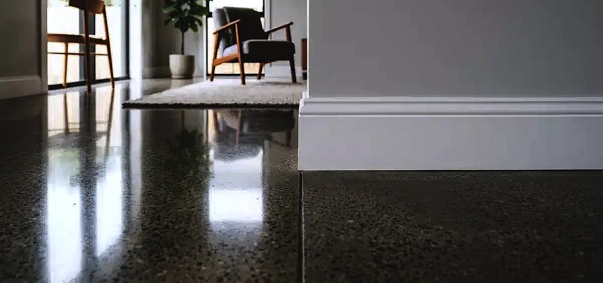 Comparison of a highly reflective polished concrete edge next to a traditional baseboard