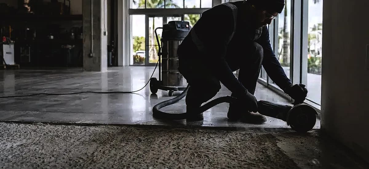 Technician using a hand-held edge grinder on a South Florida commercial concrete floor