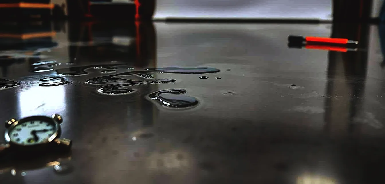 A detailed epoxy floor in a well-lit workshop setting. The smooth, glossy surface reflects the clean, bright lighting overhead.