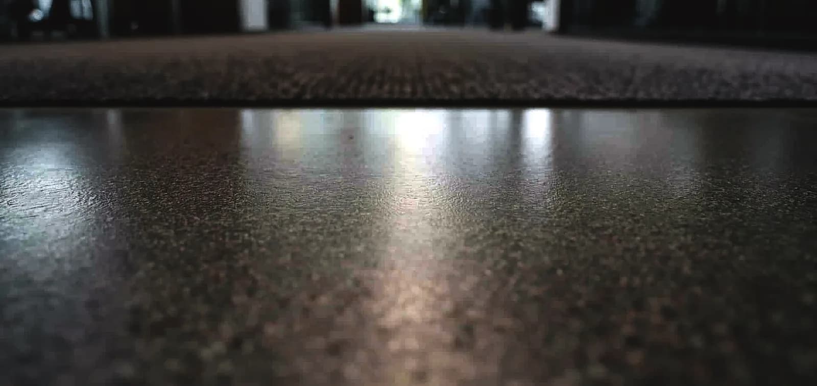 A polished concrete office floor photographed at floor level, where a carpeted zone meets the slab