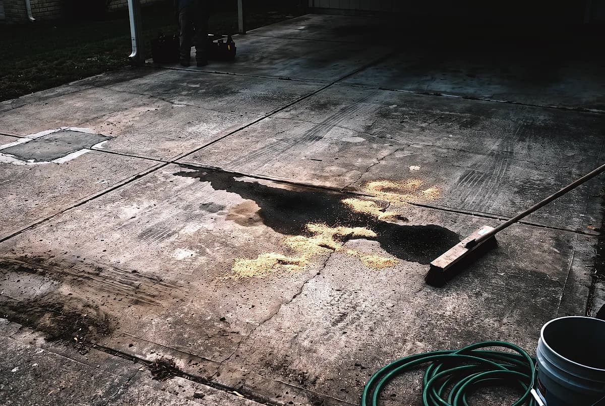 An old oil stain on a concrete driveway with absorbent granules over part of it