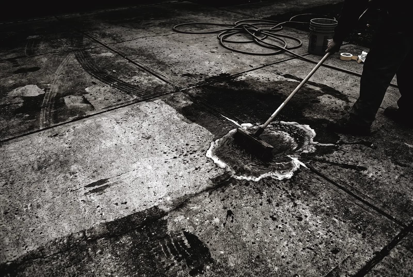 Scrubbing an oil stain out of concrete with a stiff brush