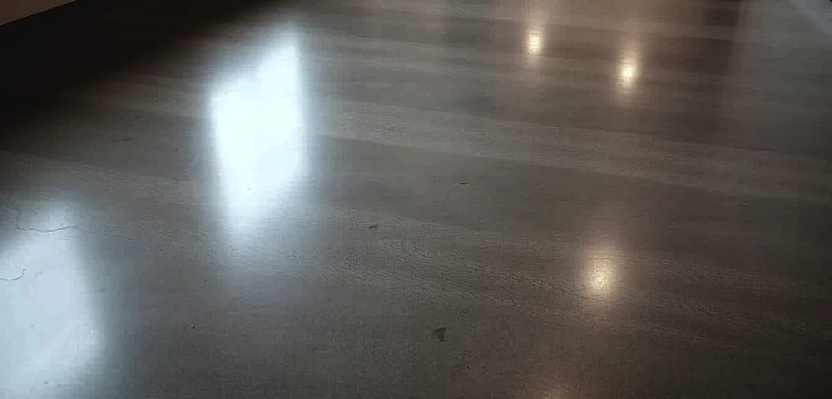 A polished concrete floor, gleaming with a lustrous sheen, illuminated by soft, diffused lighting that casts a warm, inviting ambiance.