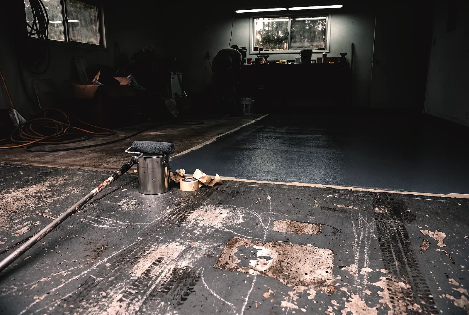 Worn grey floor paint meeting a solid even coating in a garage