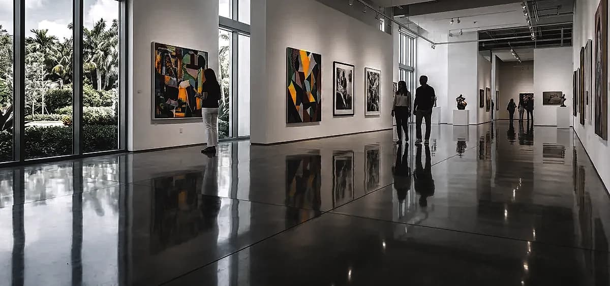 A brightly lit South Florida art gallery featuring a seamless, high-gloss museum-grade polished concrete floor reflecting contemporary artwork.
