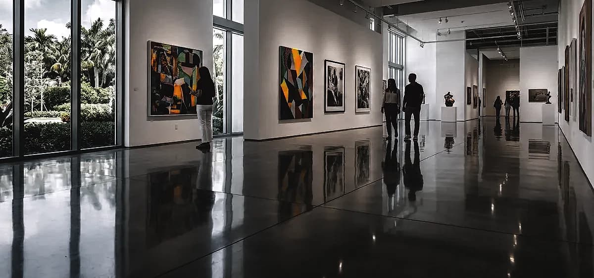 A brightly lit South Florida art gallery featuring a seamless, high-gloss museum-grade polished concrete floor reflecting contemporary artwork.