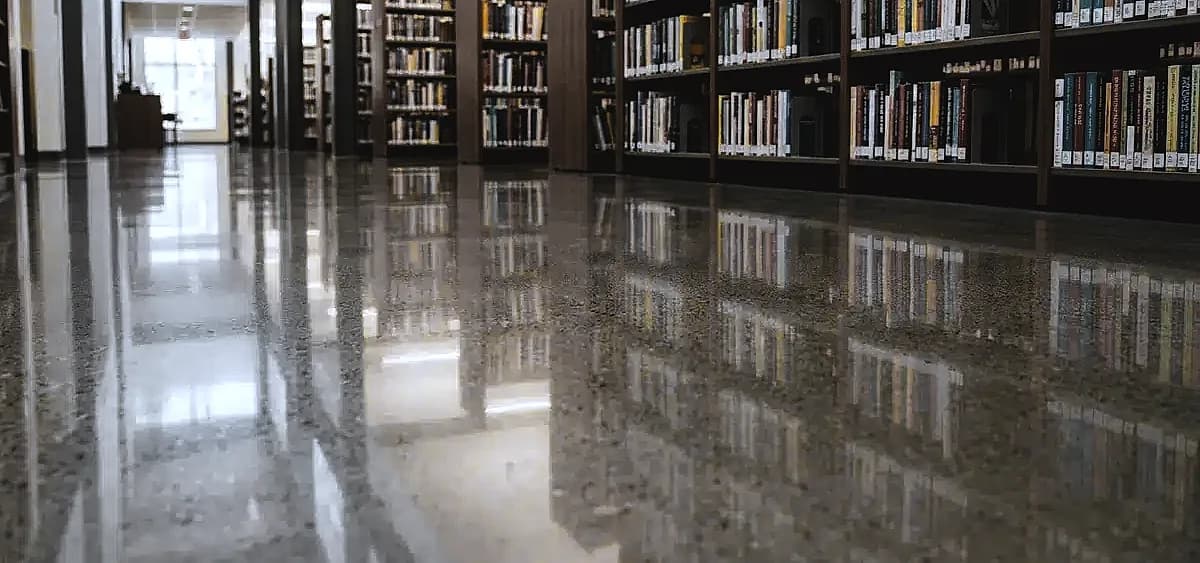 Close up of a pristine, dust-free polished concrete floor showing a clear reflection of library bookshelves