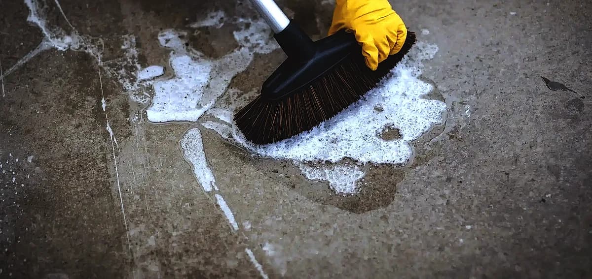 Scrubbing oil stains off a concrete floor with soapy water, a vital step for concrete polishing South Florida.