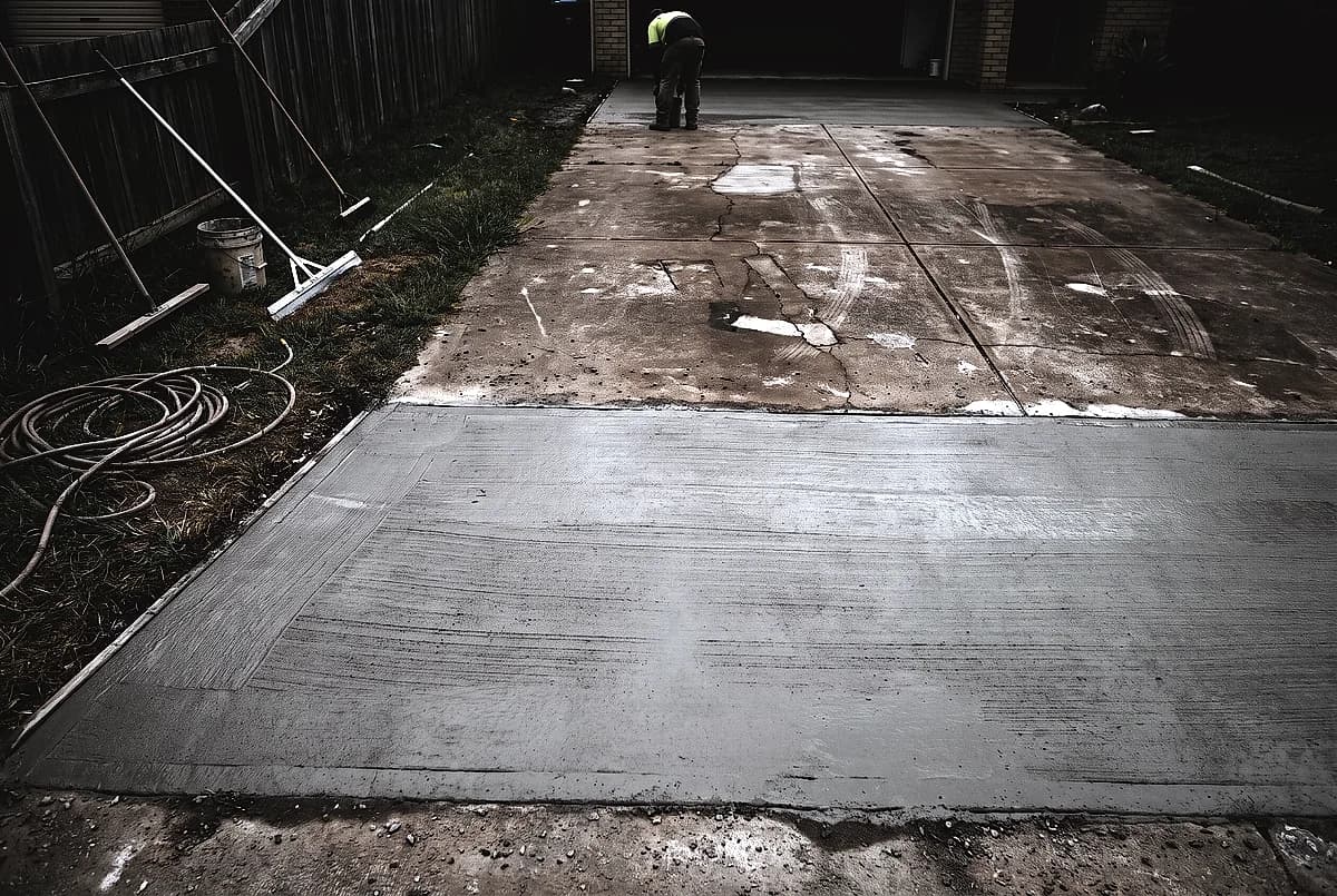 A driveway part way through resurfacing, fresh overlay beside old cracked concrete