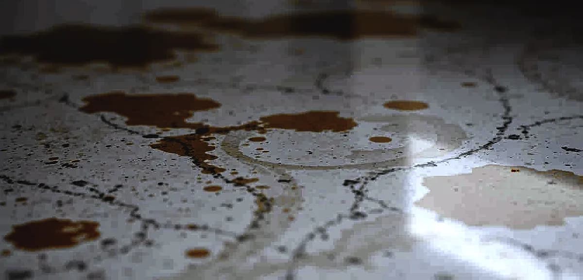 A close-up view of a section of epoxy flooring, showing distinct discoloration patches and streaks.