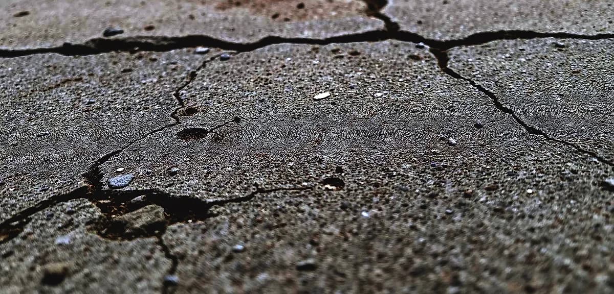 A high-resolution, macro-level photograph of a concrete substrate surface with visible imperfections and textural details.