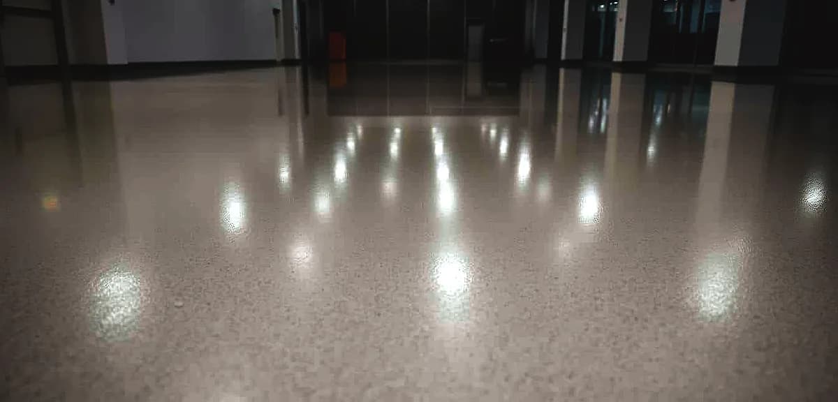 A well-lit close-up shot of a glossy, seamless epoxy resin floor surface in a sleek, modern commercial space.