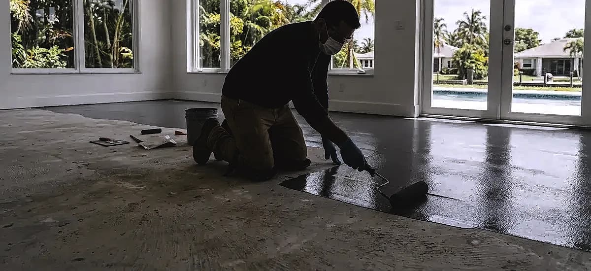 Technician applying a moisture vapor barrier to a concrete floor in South Florida
