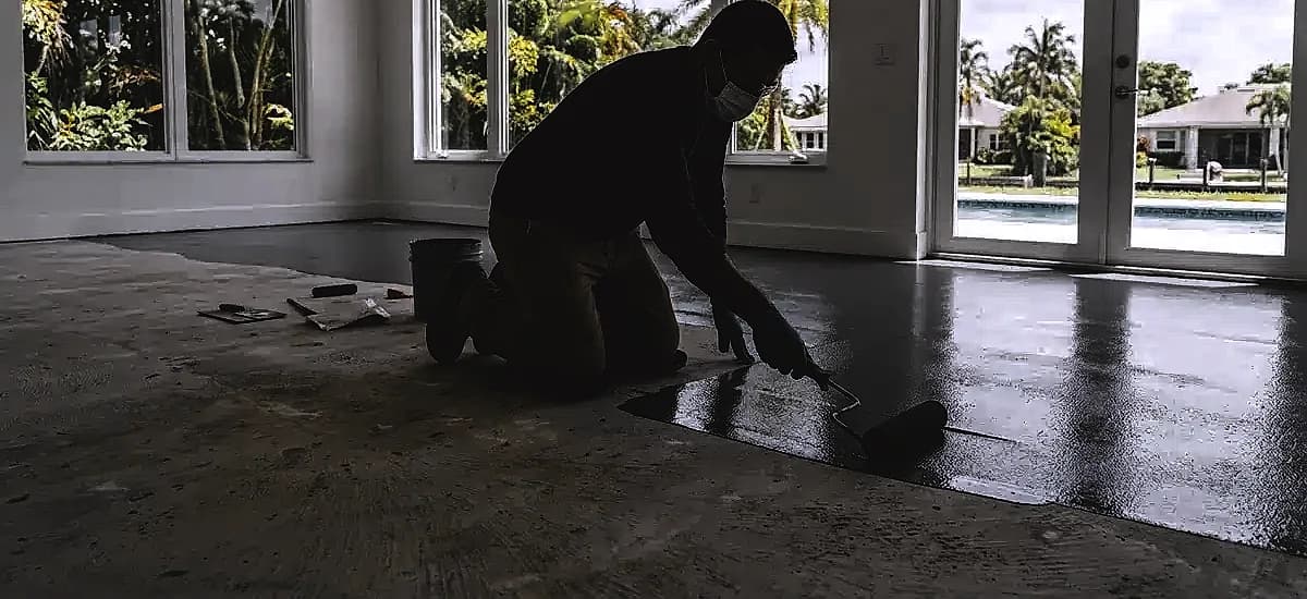 Technician applying a moisture vapor barrier to a concrete floor in South Florida