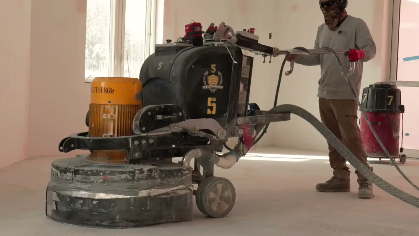 Crew grinding a concrete slab during floor preparation