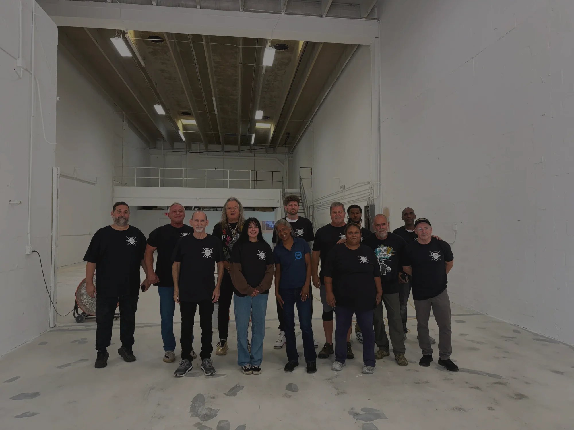 The National Concrete Polishing crew in black company shirts, lined up together in the warehouse on a finished concrete floor
