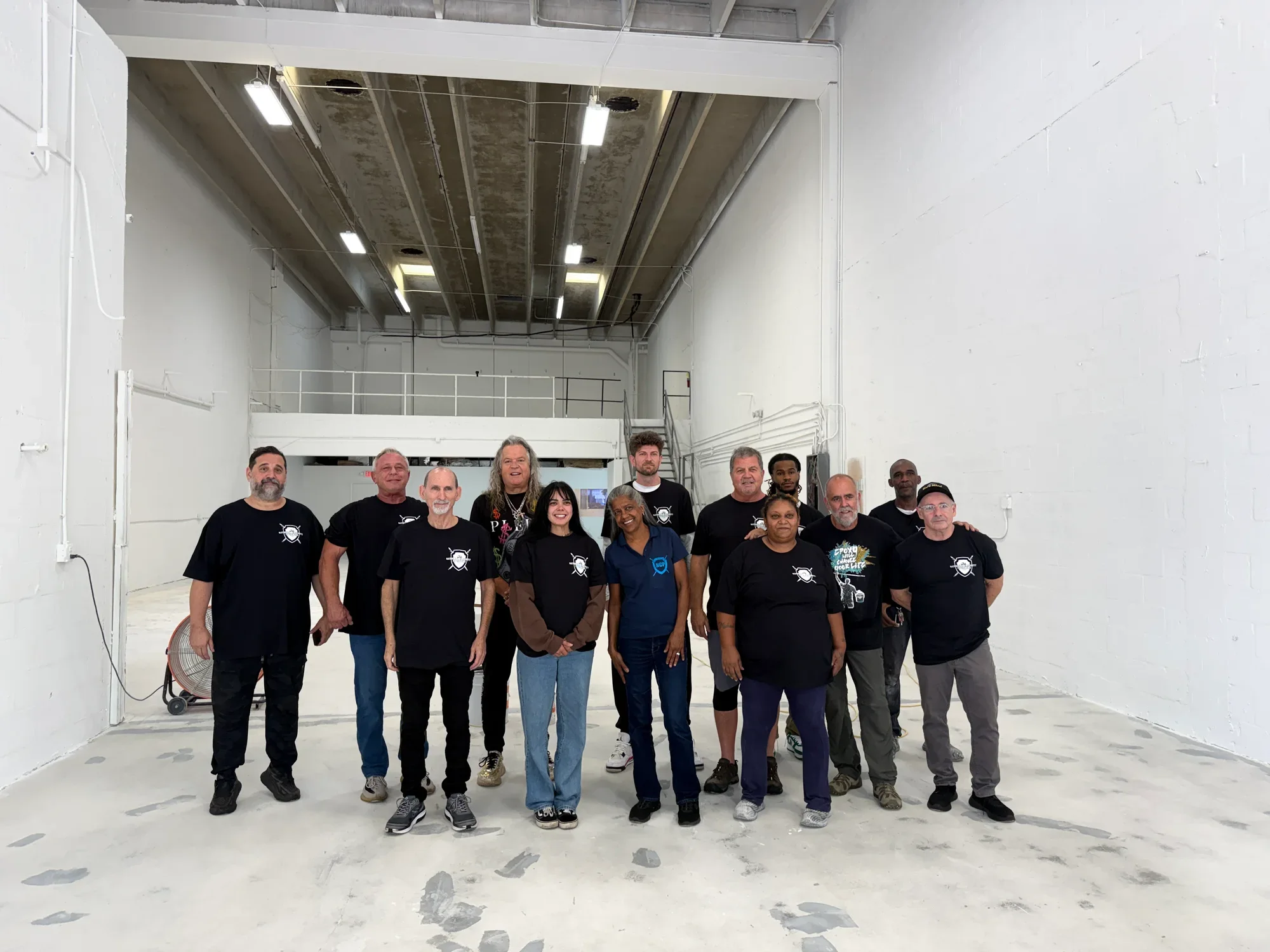 The National Concrete Polishing crew in black company shirts, lined up together in the warehouse on a finished concrete floor