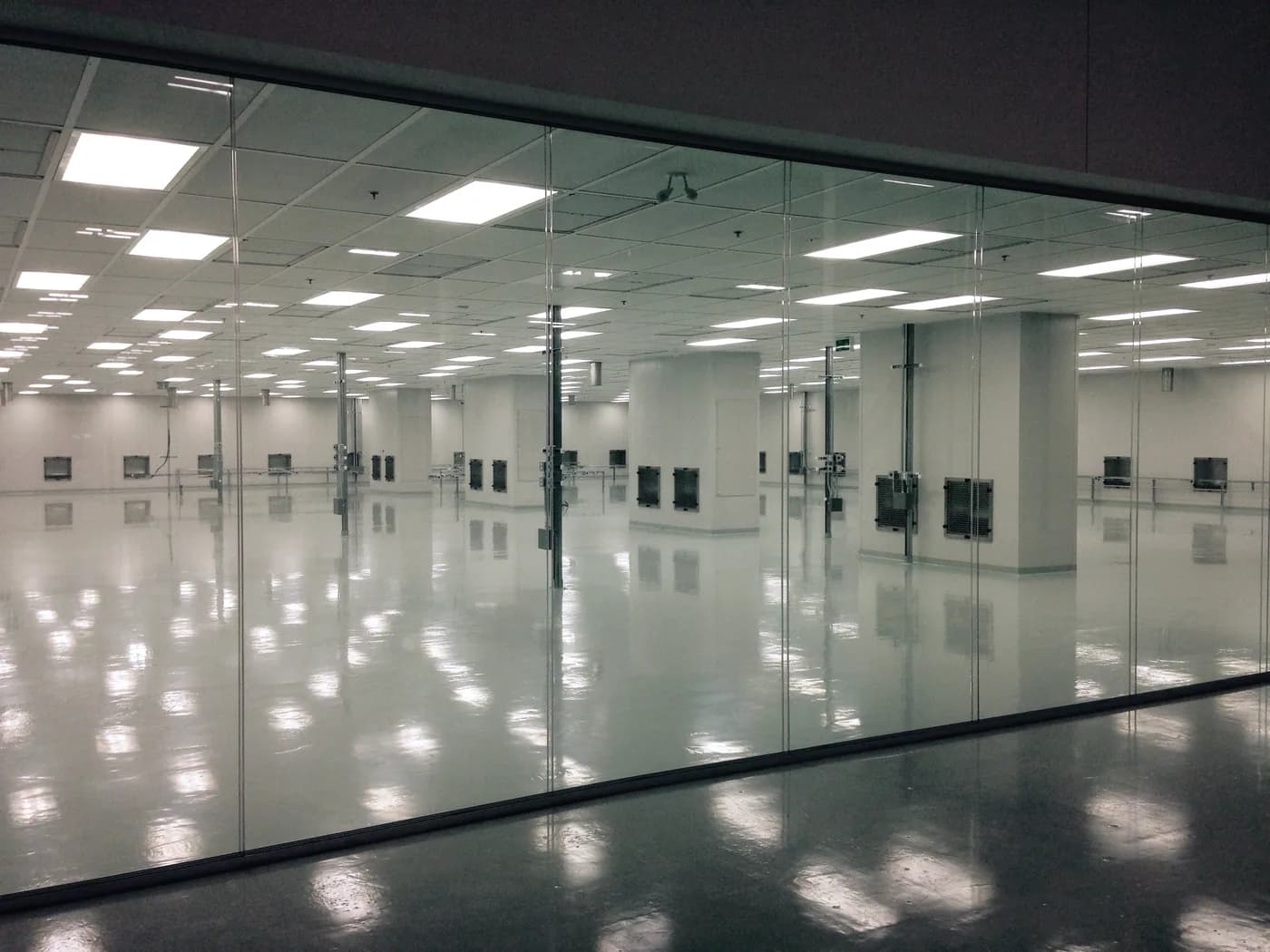 Gloss epoxy floor in a clean manufacturing hall behind a glass wall