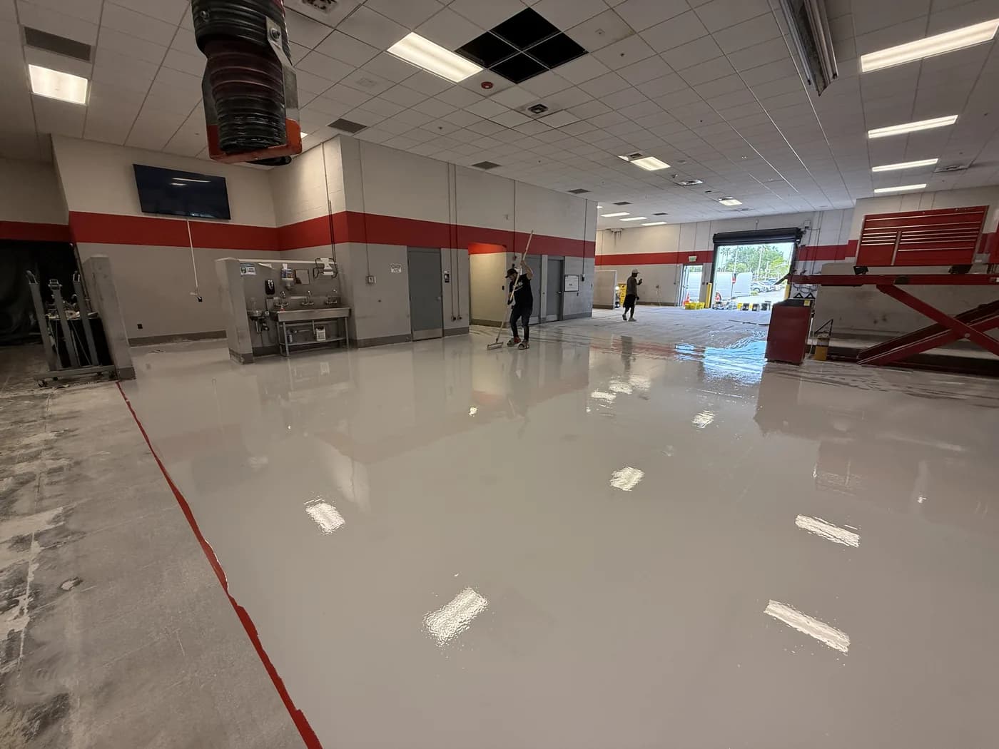 Crew finishing a gloss epoxy floor in a service department
