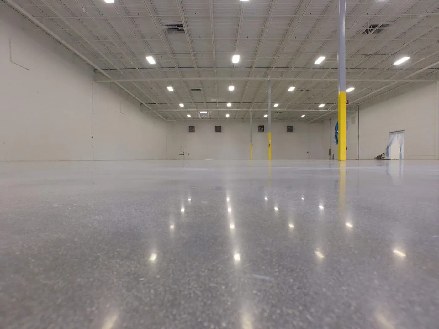 Polished concrete warehouse floor with a yellow safety column