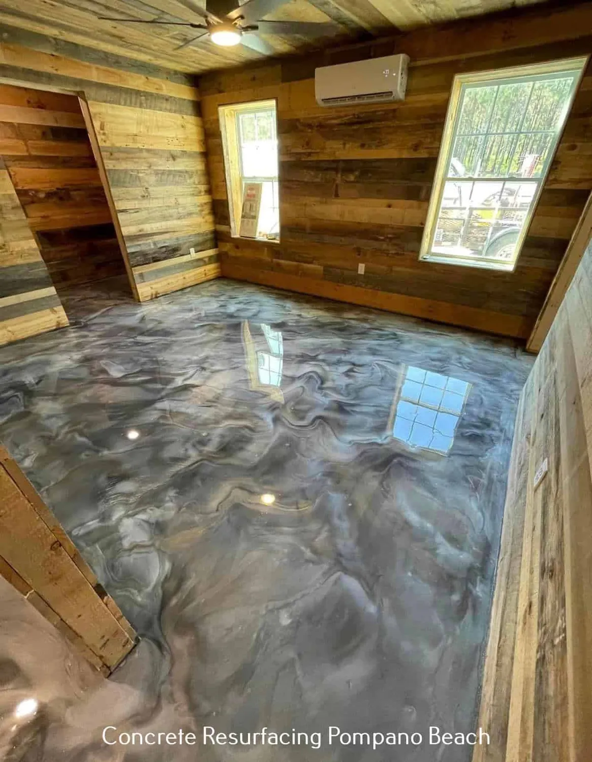A grey and white metallic floor poured through a room with reclaimed timber walls, the veining holding the light from the windows