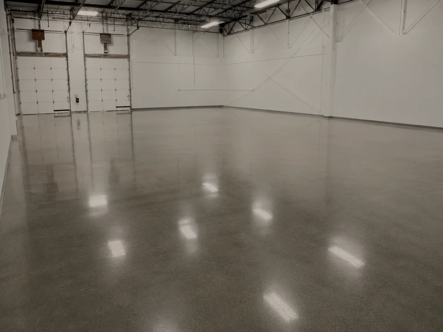 Polished concrete floor running the length of an empty warehouse bay toward the loading doors