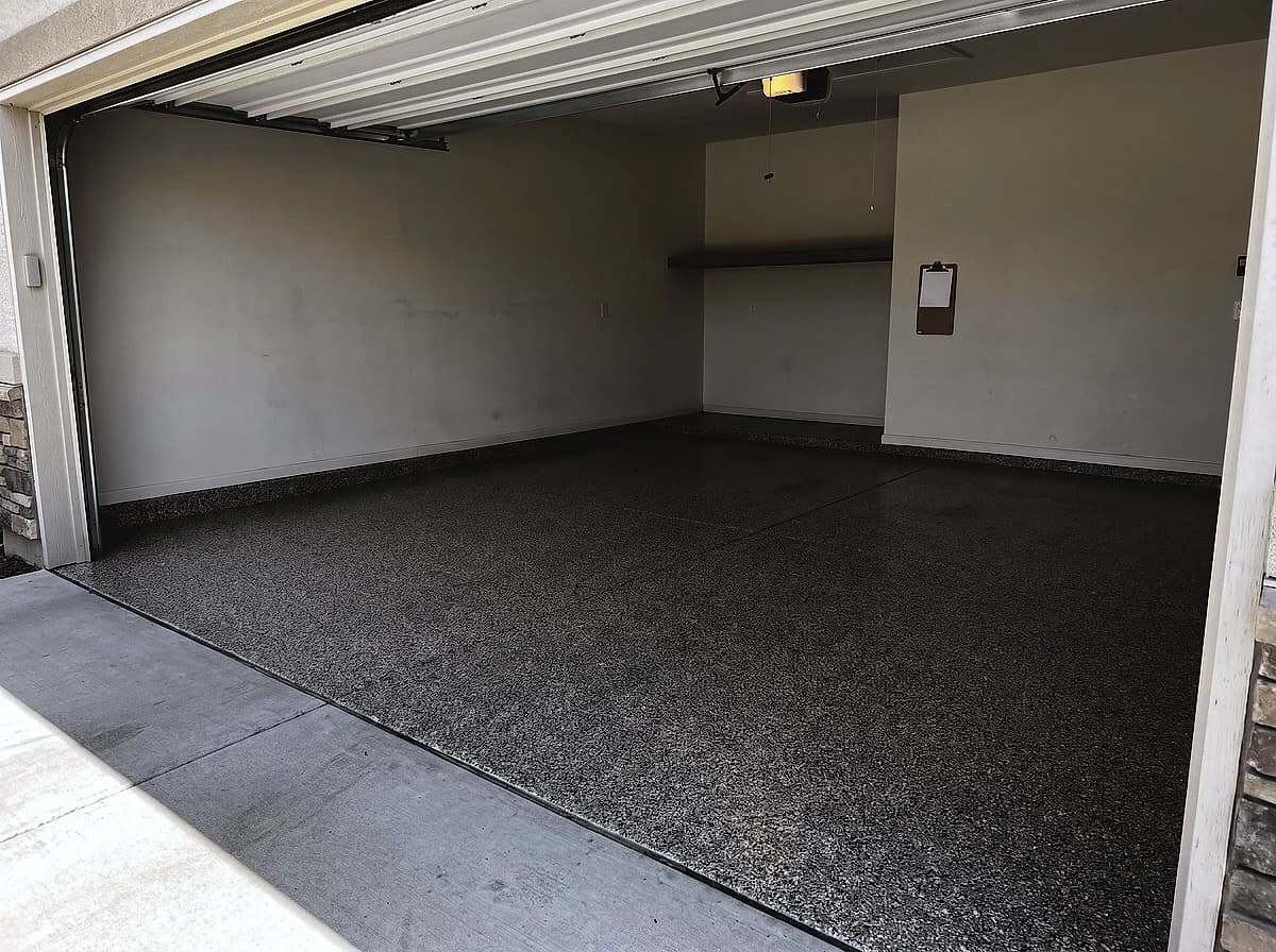 A finished flake garage floor with the door open to daylight and a care sheet on a clipboard on the wall