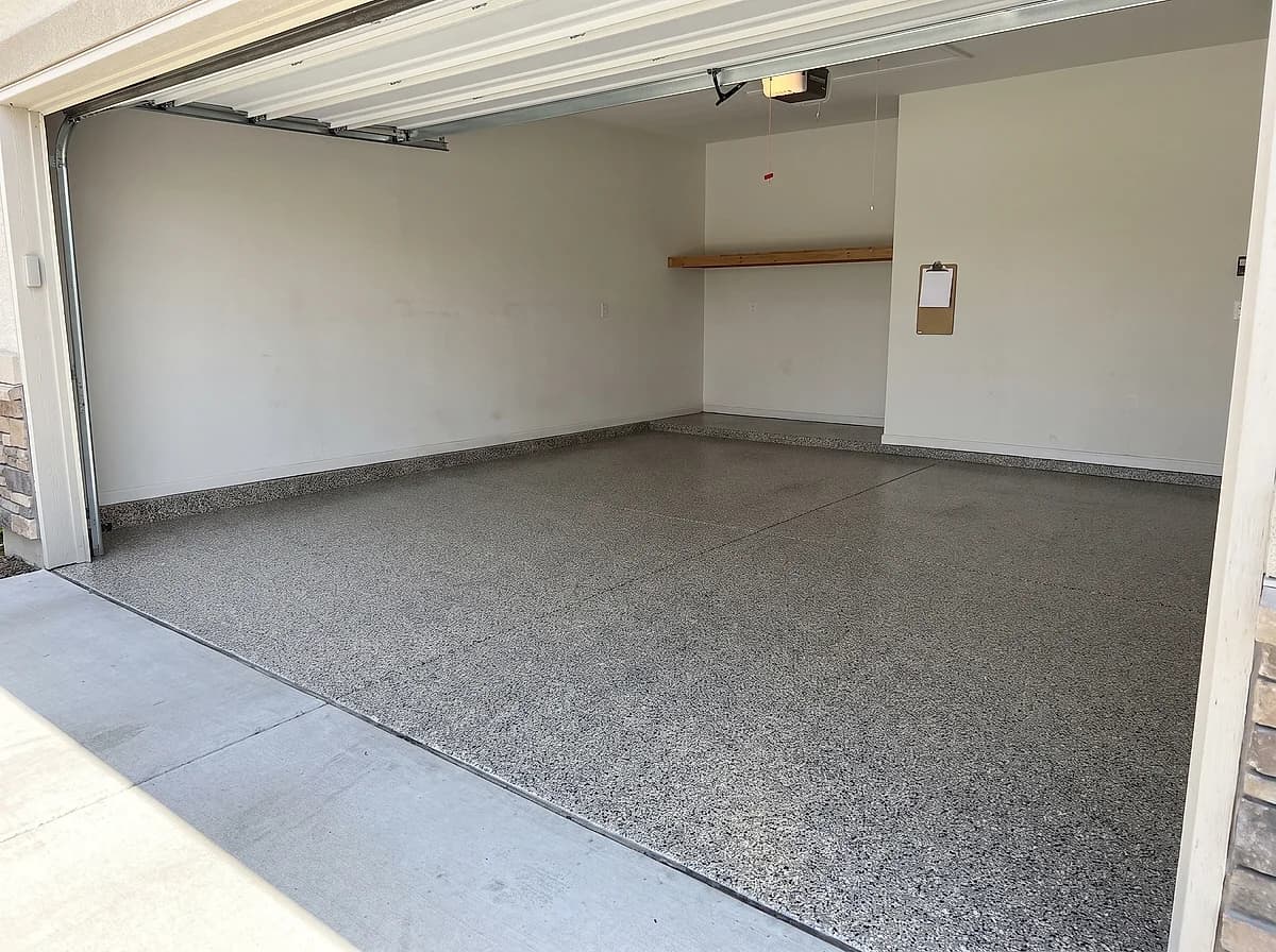 A finished flake garage floor with the door open to daylight and a care sheet on a clipboard on the wall