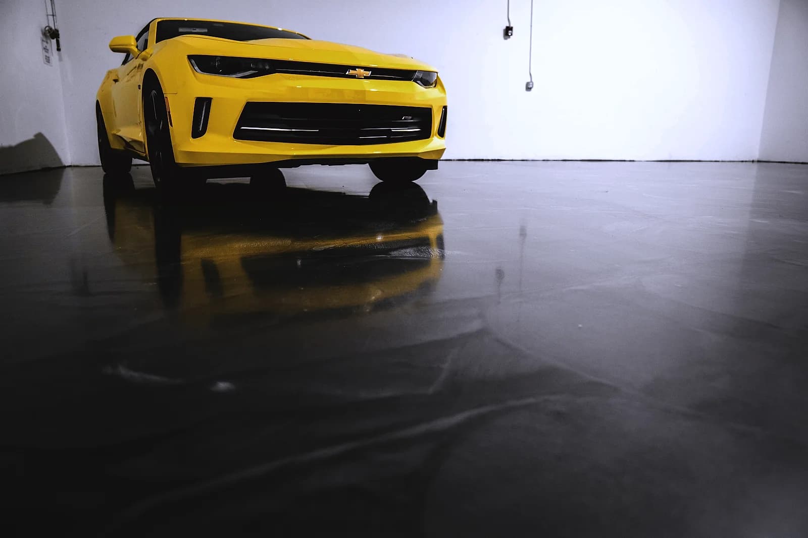 Charcoal metallic epoxy garage floor with a mirror sheen reflecting a car and the garage walls