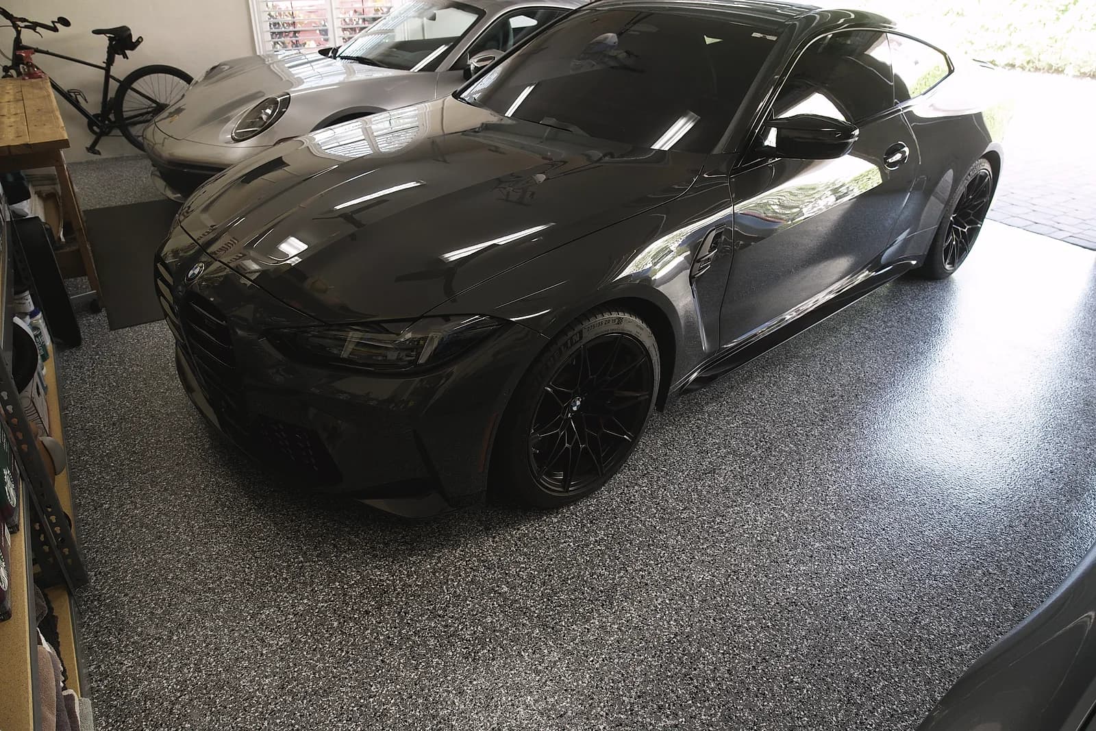 Gray and black flake garage floor with two cars parked on it, seen from the open garage door