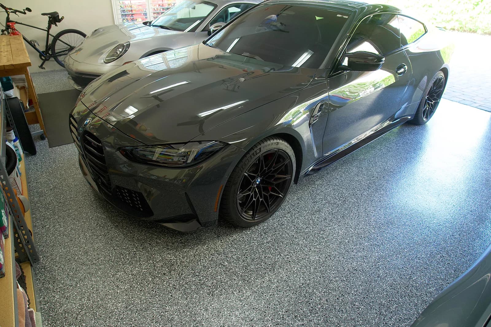 Gray and black flake garage floor with two cars parked on it, seen from the open garage door