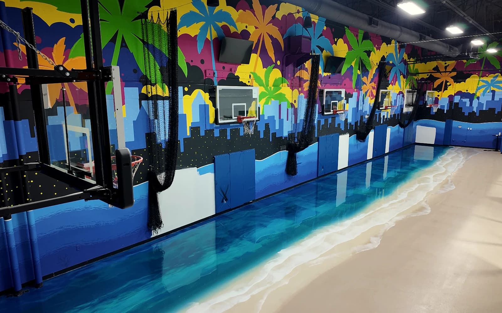 Indoor basketball court in Deerfield Beach after installation: aerial view of the finished metallic ocean floor beneath the murals and backboards