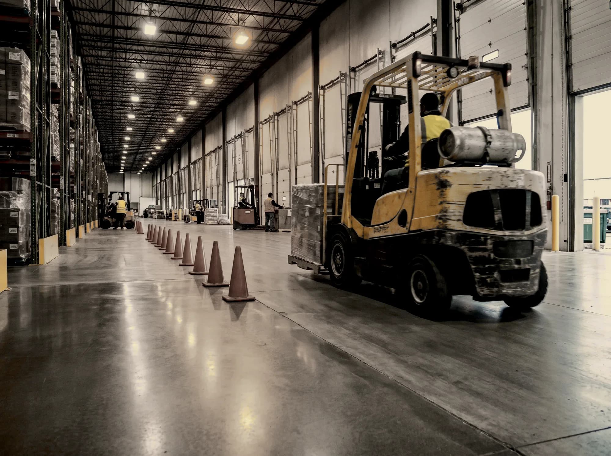 Forklift working a racked warehouse aisle while the floor installation is phased around it