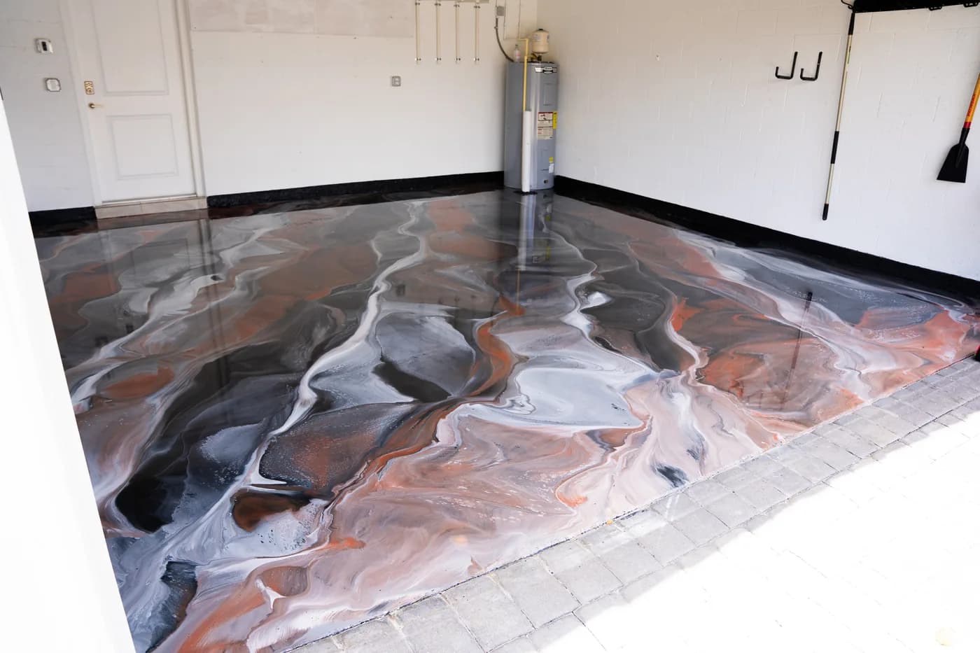 Metallic epoxy garage floor in gray, white and copper with a car parked on it