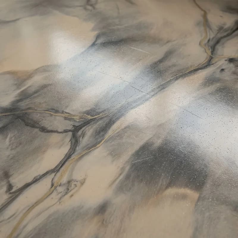 Metallic epoxy floor poured in a marble-slab effect, soft bone and oyster fields crossed by fine graphite and brass veins.