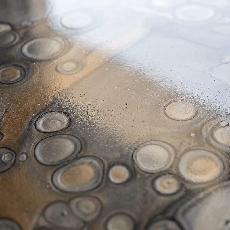 Metallic epoxy floor in a moon-crater effect, rings of graphite opening across a pewter and bronze pour.