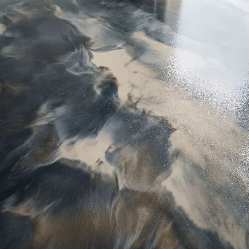 Metallic epoxy floor in a thunderstorm effect, charcoal and slate masses billowing across paler pewter openings.