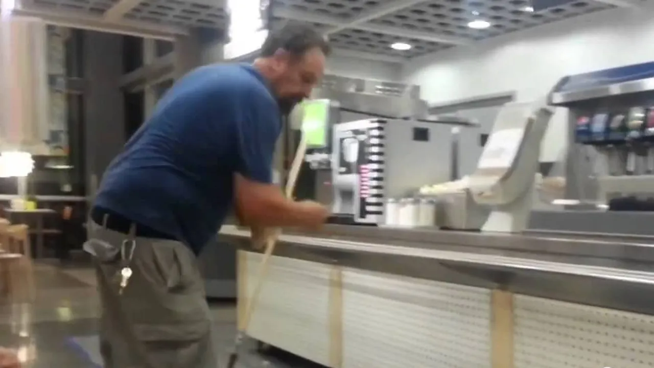 An installer drawing a coating applicator along the base of a serving counter in a store that is still fitted out
