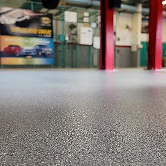 A close view of the quartz broadcast surface, its aggregate reading right up to the base of a red lift column