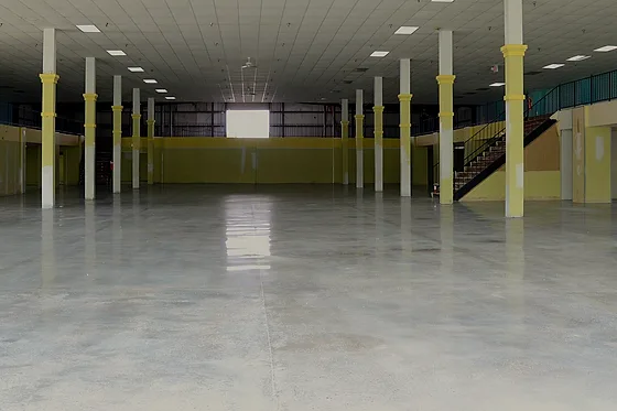 The same showroom hall empty at handover, the polished floor running clear between the columns to the far wall