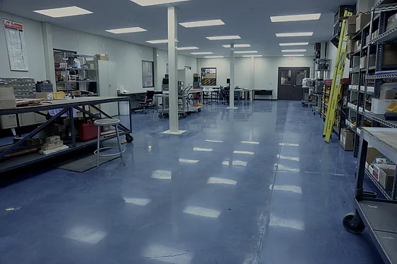 The same blue polished floor seen across the room, with component shelving and stainless benches standing on it