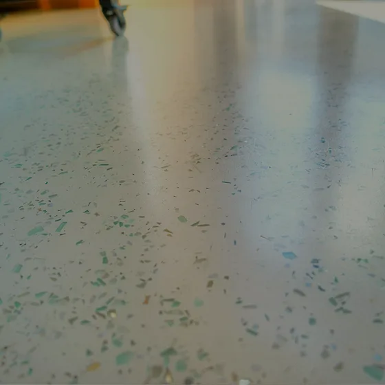 A close view of the pale floor's surface, green and grey glass aggregate reading through the polish