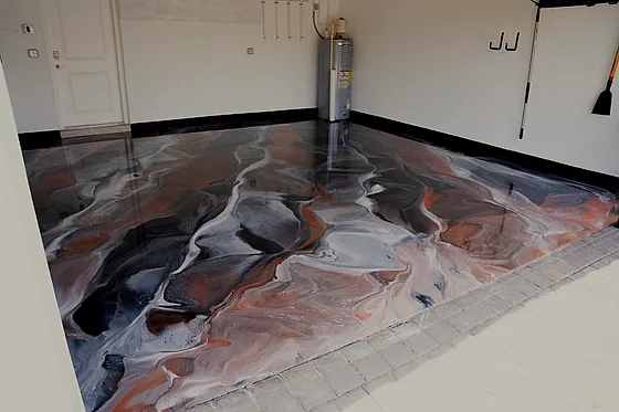 An empty home garage on a metallic floor poured in copper, white and charcoal veins, a black border running along the walls