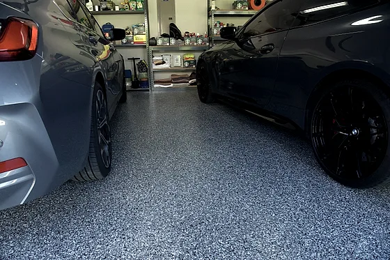 The flake floor running the full depth of the garage between two parked cars, storage shelving at the far wall